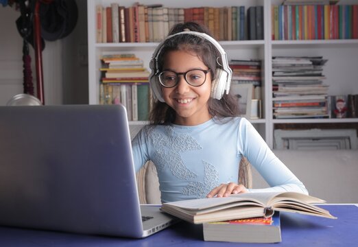 Smiling girl with headphones using laptop for school