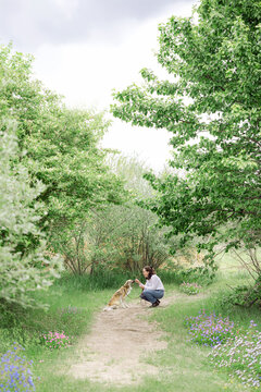 Woman crouching to pet her dog on a nature trail