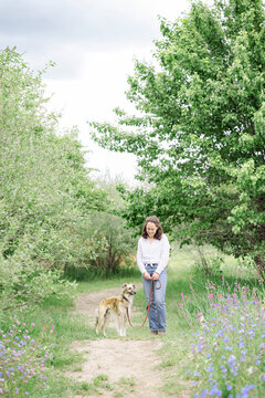 Woman and her dog walking on a lush green path