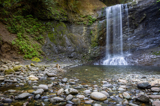 Quiet Waterfall Cascading Into Rocky Pool Surrounded by Mossy Cl