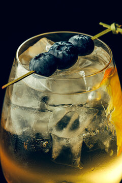 Cocktail in a glass with ice, blueberries and a lemon slice