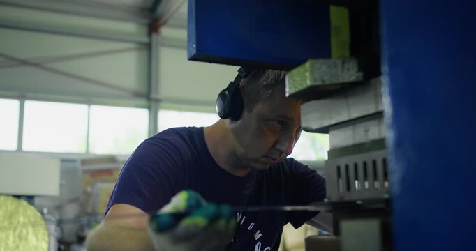 Press operator working in metalworking factory with industrial machine. Blue collar profession and manufacturing process