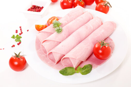 cooked ham slices rolled on white plate with fresh cherry tomatoes and basil food photography