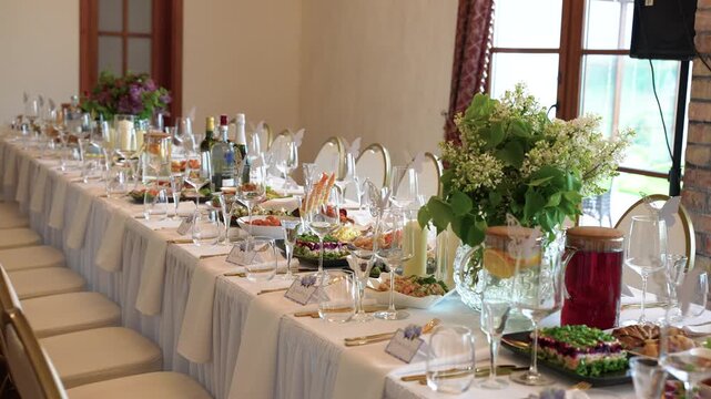 Beautiful banquet table adorned with gourmet dishes, wine bottles, glassware, and lush floral centerpieces in soft natural light. Elegant decor and fine dining create a festive, inviting mood.
