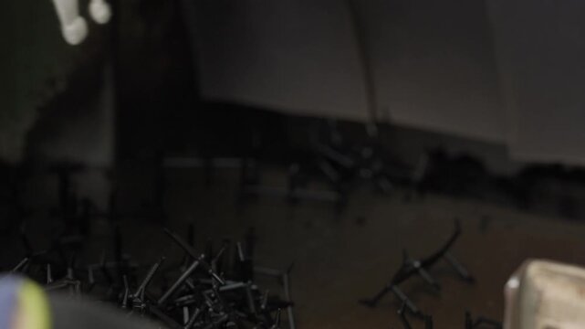 Gloved worker hand pushes scattered rigid plastic pieces into industrial shredder machine on conveyor close up