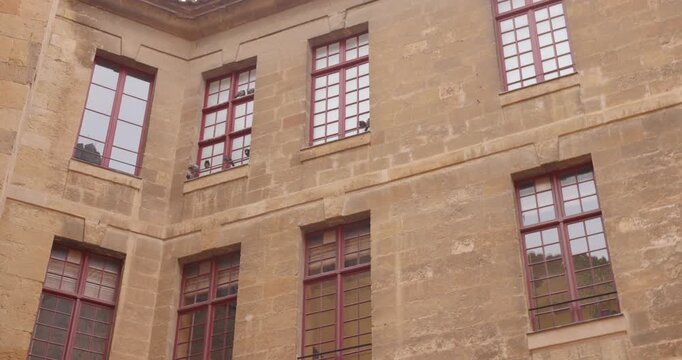 Exterior Courtyard Of The Palace Of The Archbishops Of Narbonne In France, With Pigeons Perched Along Window Ledges, low angle shot