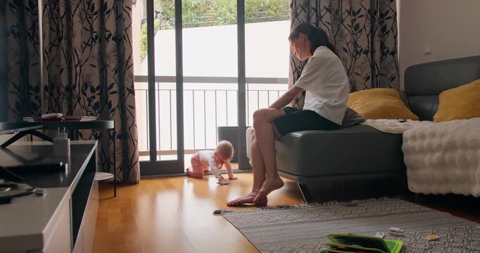Infant crawling on floor near mother in living room, early child development and home environment