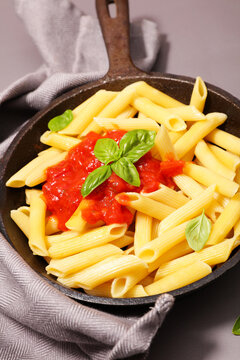 penne pasta with tomato sauce and fresh basil leaves in iron skillet pan