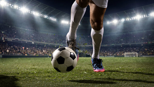 Soccer player dribbling ball close up in night stadium. Concept of footwork, tactical control, pro training, sport footwear ads, match graphics, and team strategy content.