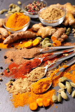 Spices background, turmeric, ginger and powder in spoons on slate
