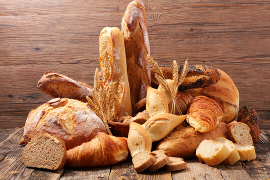 Bakery assortment with baguettes, crusty bread, croissants and wheat on wooden background