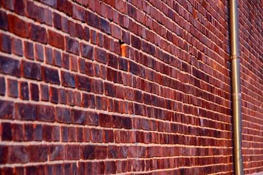 Ziegelwand mit Fallrohr im Abendlicht