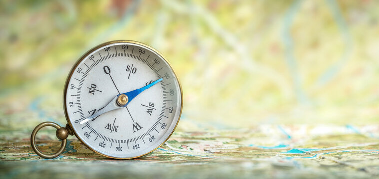 Magnetic compass on world map. Travel, geography, navigation, tourism and exploration concept background. Macro photo. Very shallow focus.