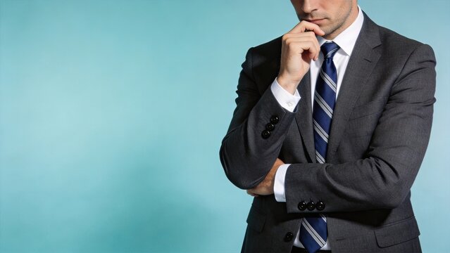 Portrait of pensive businessman in suit standing against blue background, thinking about strategy, deep thought and decision making concept