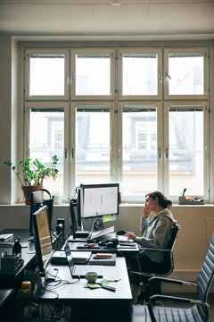 High angle view of female corporate entrepreneur working on desktop PC while sitting at desk in office