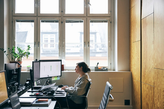 Female business professional using dual desktop PC while working in new tech office