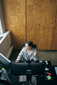 High angle view of female business expert working on dual computer in startup office