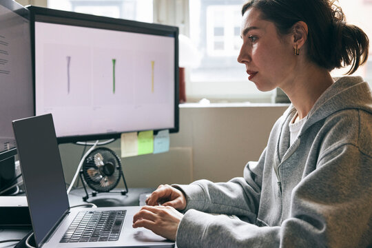 Focused female entrepreneur working on laptop while sitting at desk in office