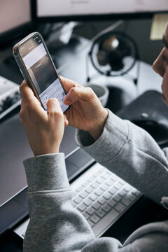 High angle view of businesswoman drafting email in smart phone while working at startup office