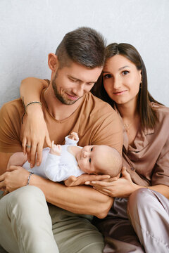 Loving Parents Holding Smiling Baby At Home