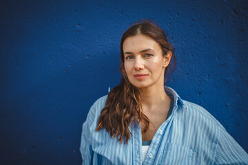 Confident young woman posing against blue wall