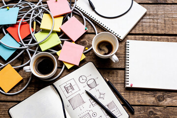 Naklejka premium Messy creative brainstorm desk from above, sticky notes cables and coffee cups in an organic flat lay with copy space for text