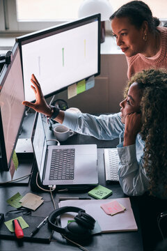 High angle view of businesswoman sharing design ideas with female coworker on computer in tech startup office