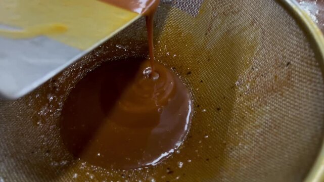 Caramel cooking process in industrial food production. Heated sugar mixture being cooked in a stainless steel kettle to develop color, flavor, and texture for food manufacturing applications.
