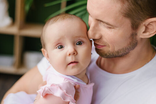 Father Holding Infant Daughter With Gentle Expression