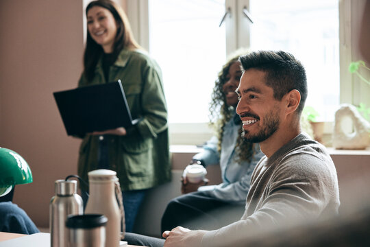 Smiling mature businessman sitting in office meeting with tech colleagues