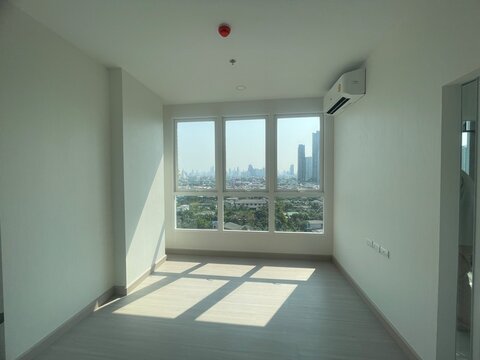 Empty condominium room with large window and city view background.