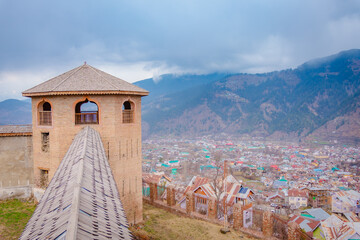 Ancient stone watchtower overlooking a scenic mountain town in the valley of Kashmir, India © 3 Travelers
