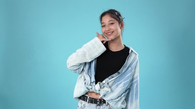 Young woman making a call me hand sign gesture on blue background