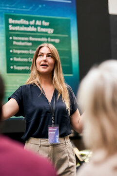 Blond female speaker giving presentation to business audience at convention hall