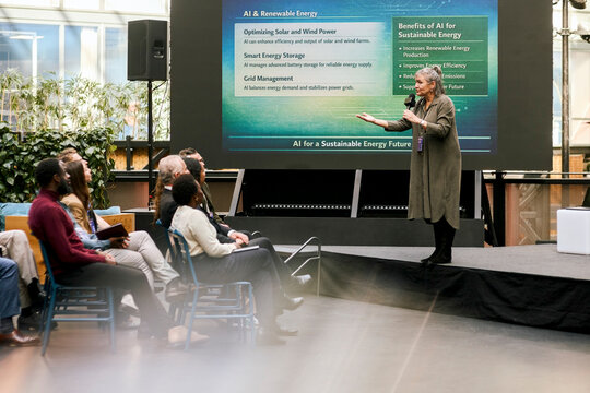 Senior female professional speaker addressing audience while giving presentation speech at seminar in convention center