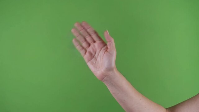 Woman's arm waving her hand to say hello or goodbye. Friendly greeting gesture isolated on a green screen for easy chroma keying