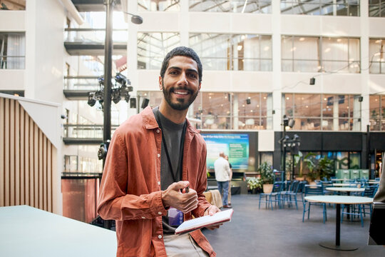 Portrait of smiling male entrepreneur with note pad in convention center seminar
