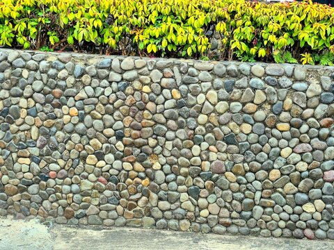 Natural round pebble stone wall in a beautifully landscaped garden