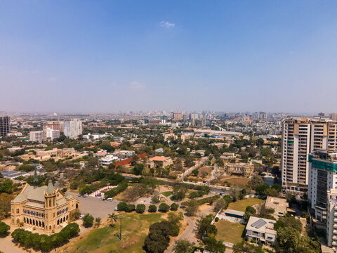Aerial view of the historic Frere Hall building surrounded by lush green gardens and the sprawling urban skyline in Karachi, Sindh, Pakistan.