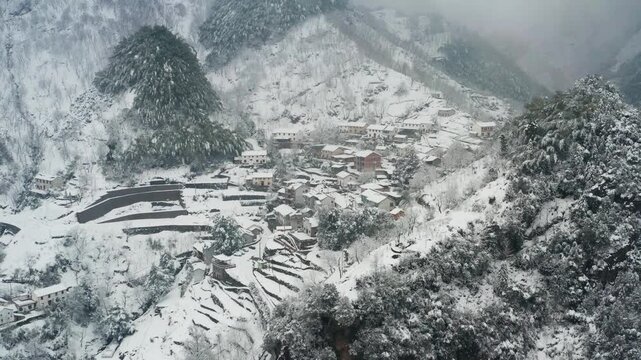 Aerial view of snowy mountain village with terraced fields in winter