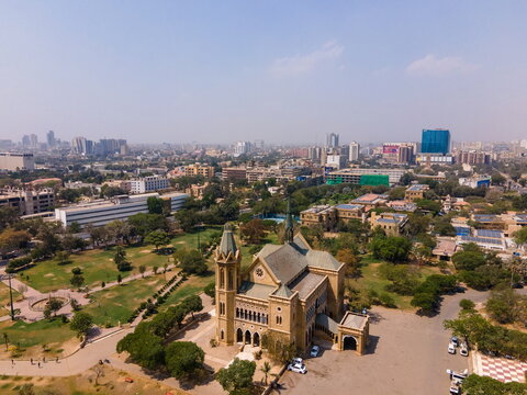 Aerial view of Frere Hall featuring Venetian Gothic architecture surrounded by lush green gardens and the urban skyline of Karachi, Sindh, Pakistan.