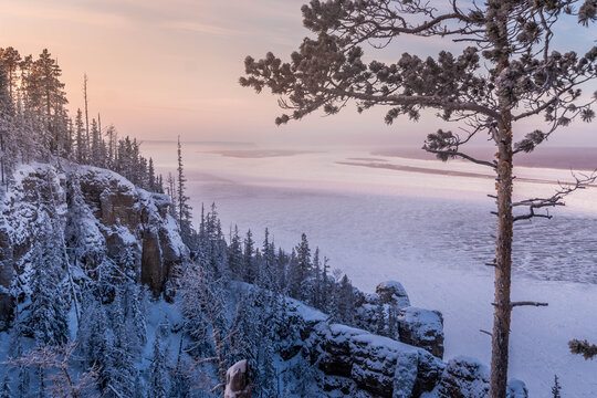 Cold subarctic winter at Lena River in Yakutia, Siberia, Russia, frozen waterway through snow covered taiga forest and rocky cliffs. 
