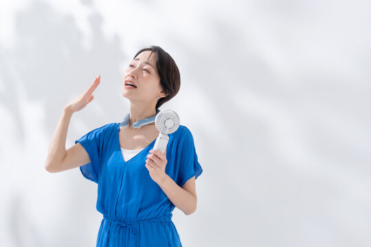 ハンディファンとネッククーラーを使う女性　