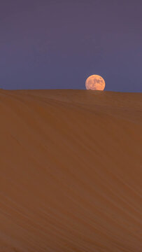 Lunar moonrise over Saharan wilderness in Chad, vast empty desert under glowing full moon at night. 
