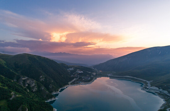 aerial view captures expansive Lake Kazenoy-Am nestled between steep green mountains under a sunset sky
