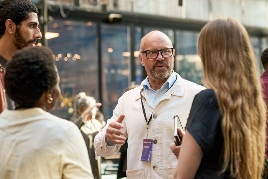 Senior businessman networking with associates at event in convention center
