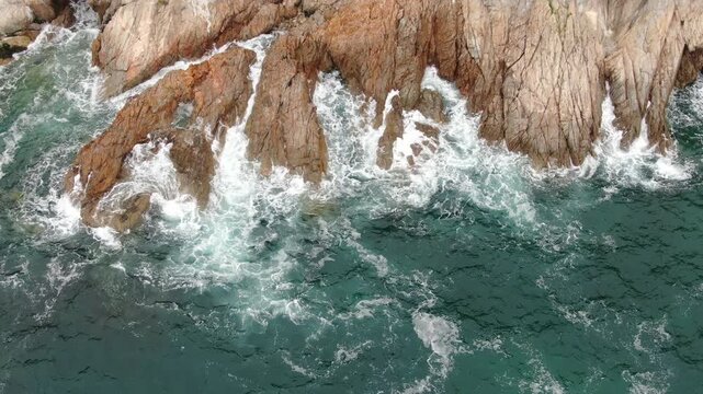 Aerial View of Ocean Waves Crashing Against Rocky Coastline