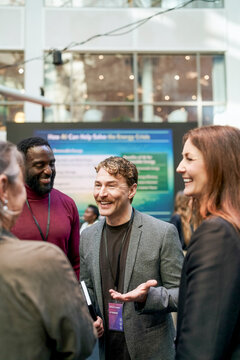 Happy male business professional discussing collaboration ideas with executives at meet and greet event in convention ce