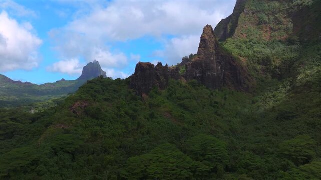 Belvedere Lookout Moorea Tahiti island French Polynesia Mount Toheia Mt Rotui aerial drone lush green jungle forest volcanic jagged rugged mountain peaks sunny morning blue sky clouds upwards motion