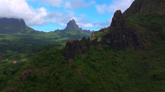 Belvedere Lookout Moorea Tahiti island French Polynesia Mount Toheia Mt Rotui aerial drone lush green jungle forest volcanic jagged rugged mountain peaks sunny morning blue sky clouds forward pan up
